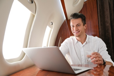 Image of Handsome man working with laptop on plane. Comfortable flight