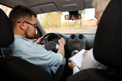 Photo of Man and instructor in car. Passing driving license exam