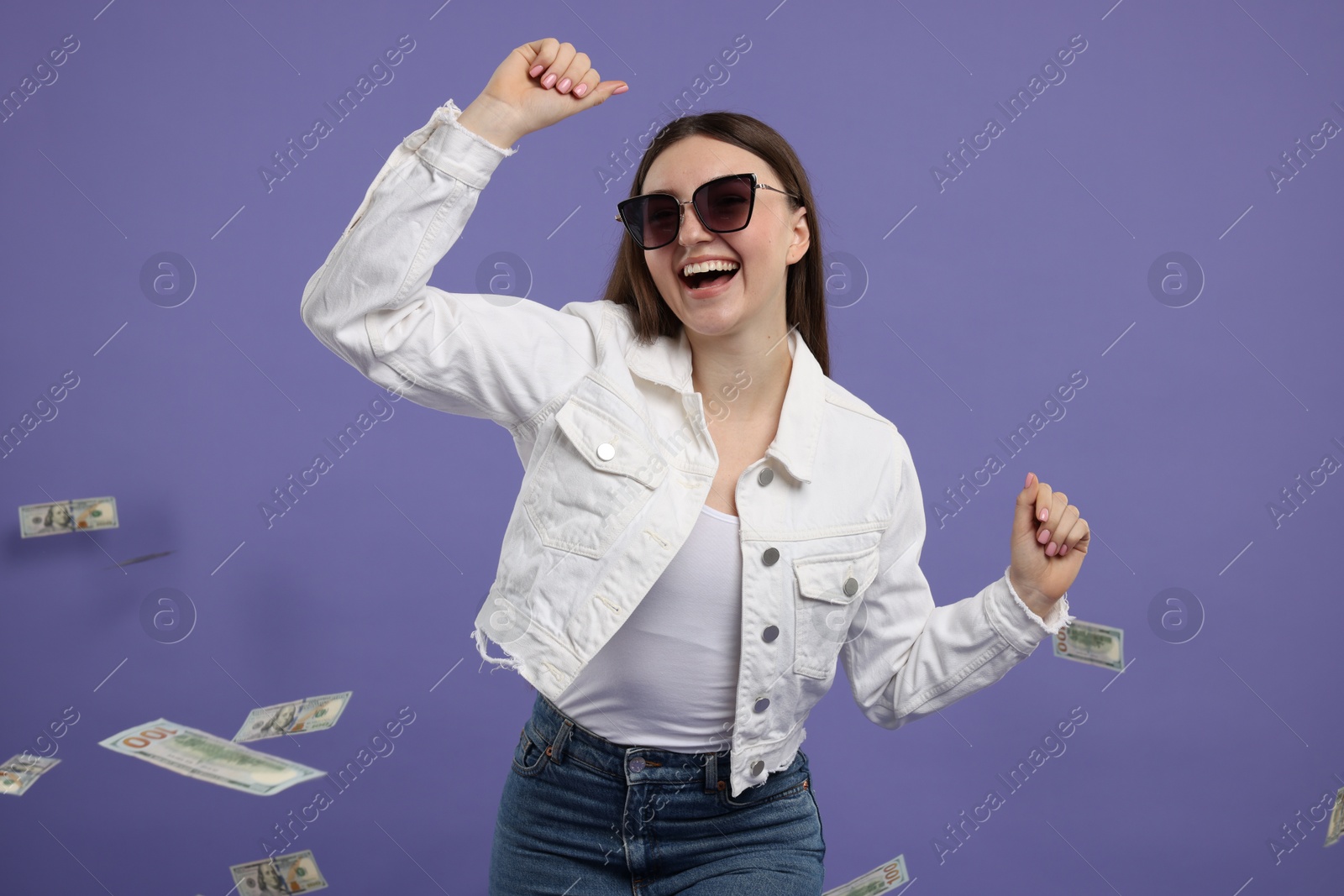 Photo of Happy woman under money shower on purple background