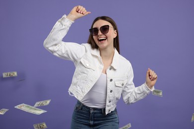 Happy woman under money shower on purple background