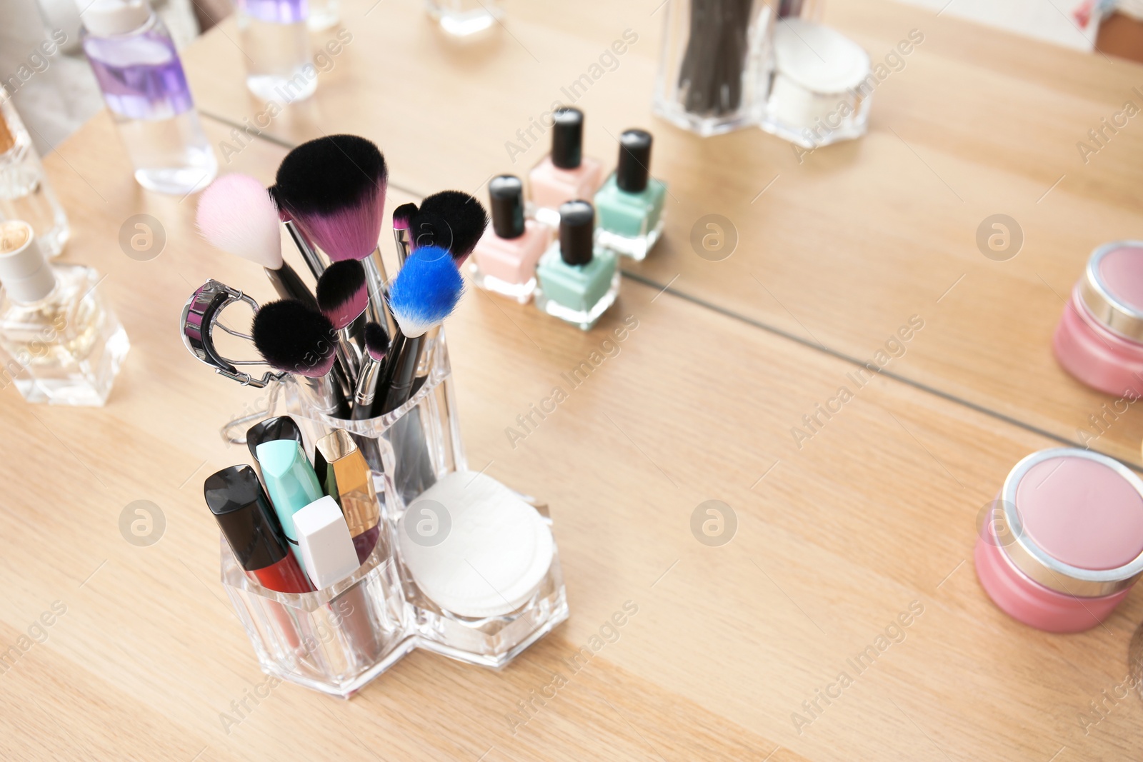 Photo of Organizer with makeup cosmetic products on wooden table near mirror