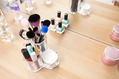 Organizer with makeup cosmetic products on wooden table near mirror