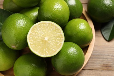 Photo of Whole and cut fresh limes on table, closeup