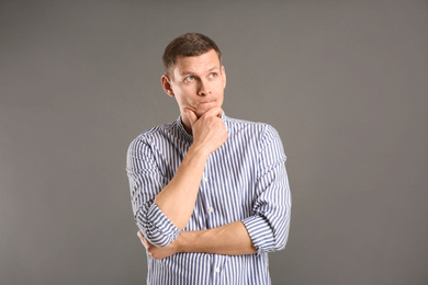 Photo of Thoughtful man in casual outfit on grey background