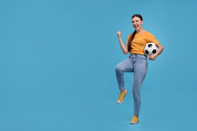 Photo of Happy soccer fan with ball celebrating on light blue background. Space for text