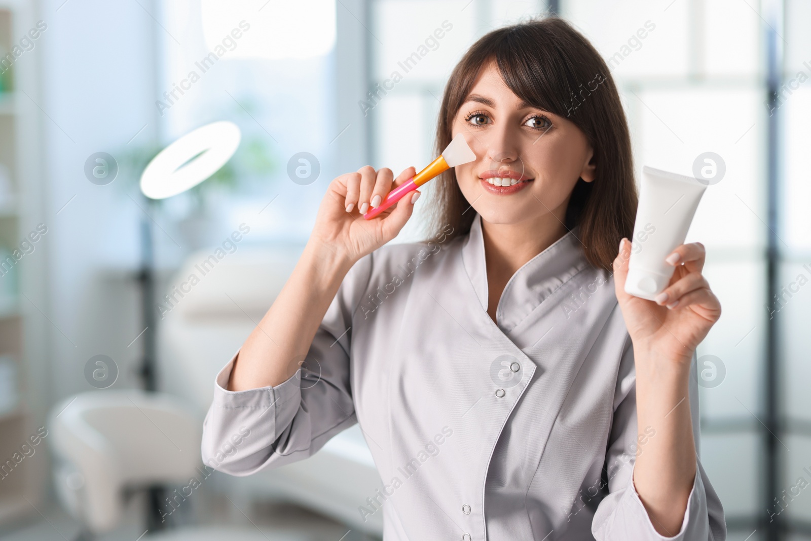 Photo of Cosmetologist with silicone brush and cosmetic product in clinic