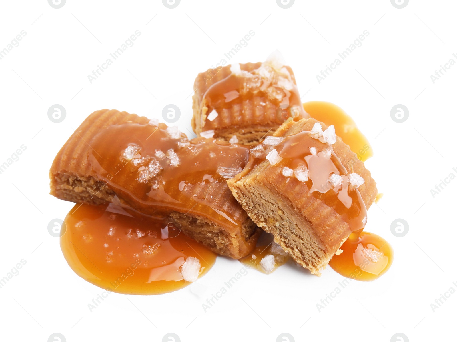 Photo of Yummy caramel candies and sea salt isolated on white