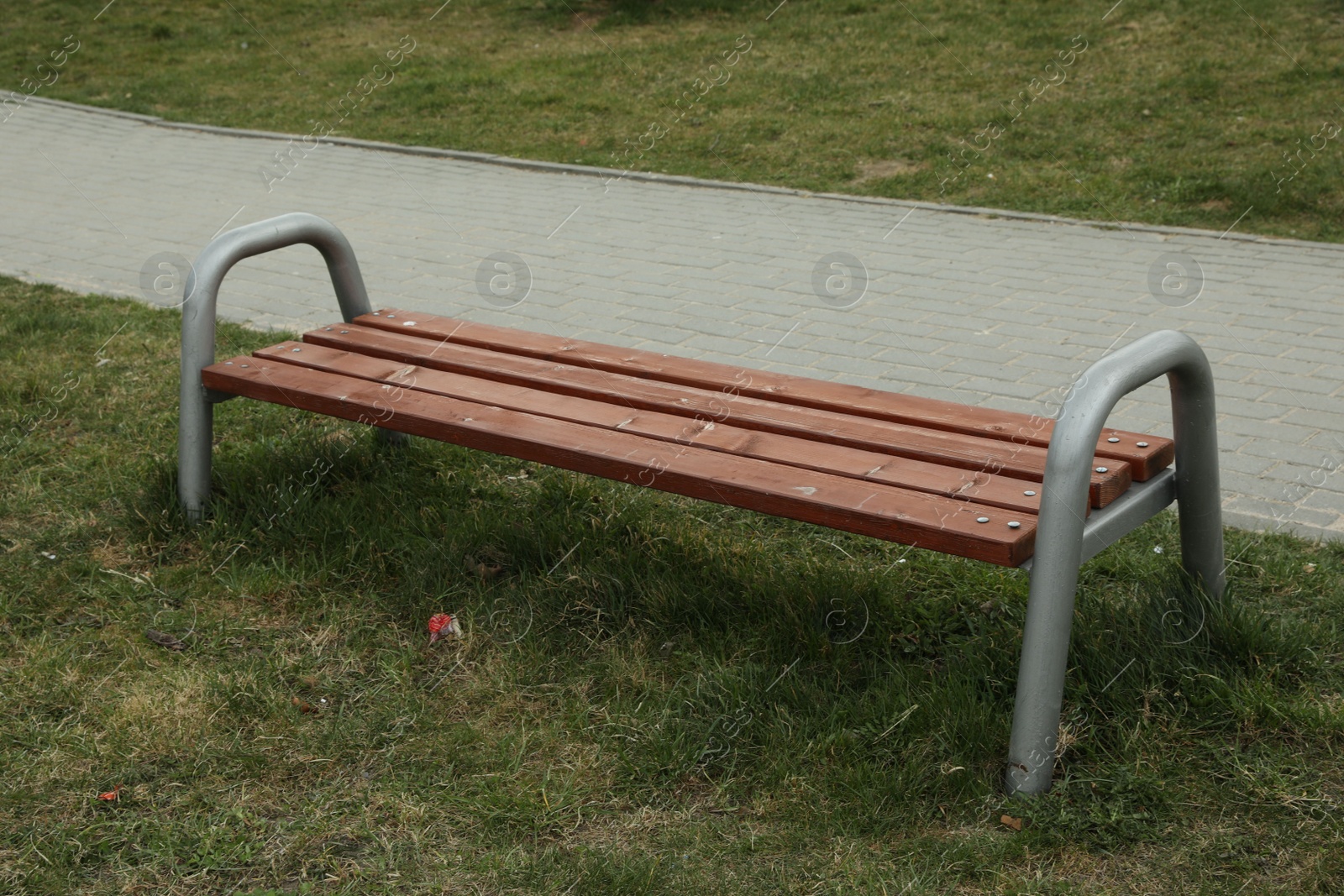 Photo of Modern wooden bench on green grass outdoors