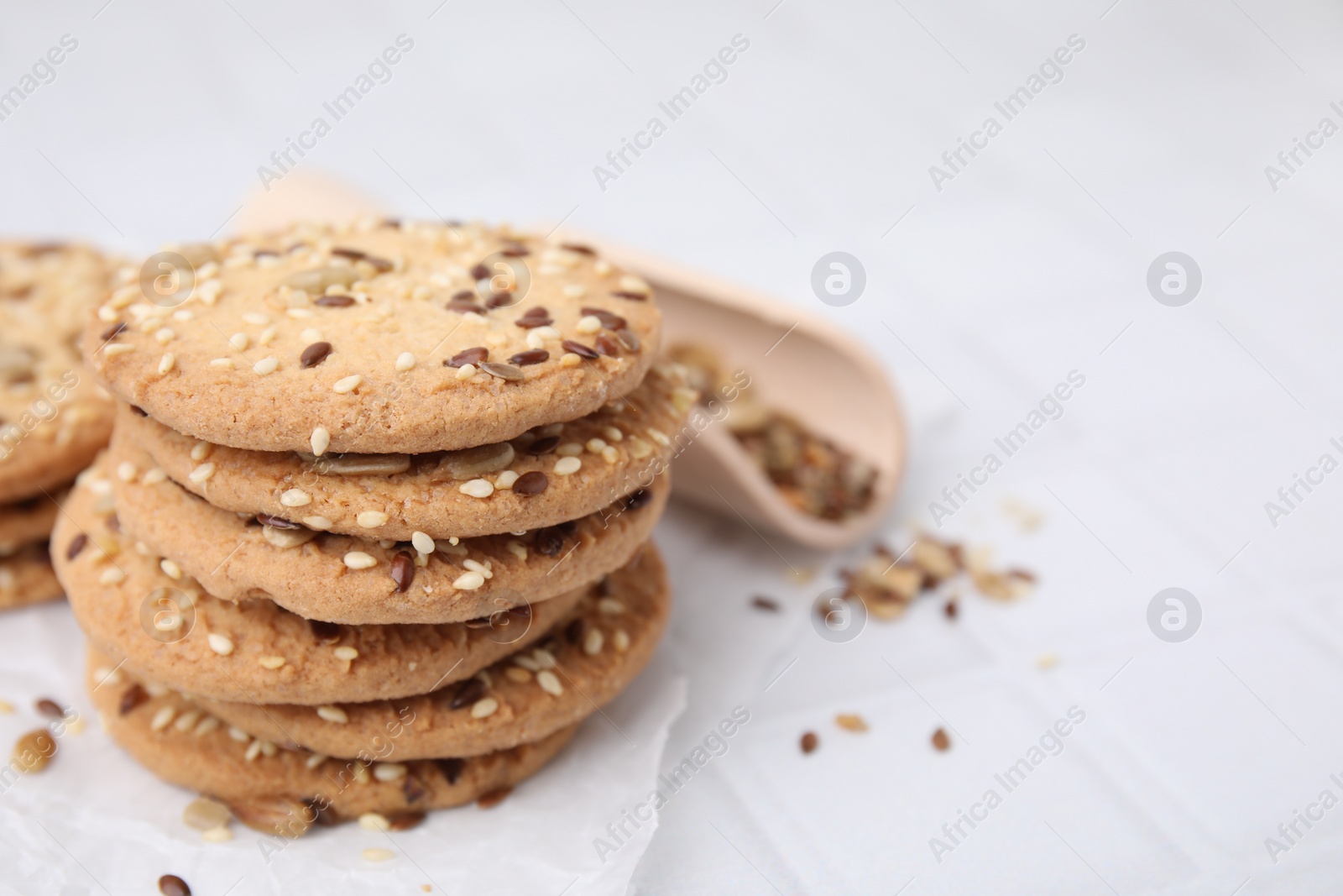 Photo of Cereal crackers with flax and sesame seeds on white tiled table, closeup. Space for text