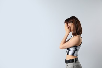 Photo of Young girl hiding face in hands on white background. Space for text