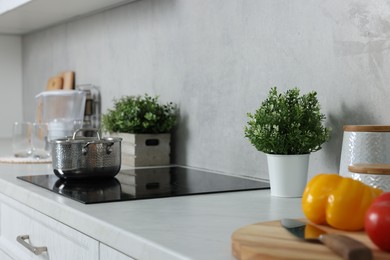Photo of Potted artificial plants on white countertop in kitchen