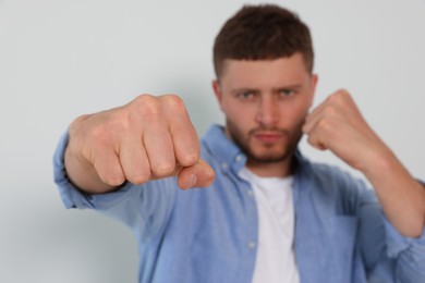 Photo of Young man ready to fight against white background, focus on hand. Space for text