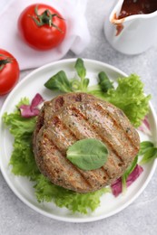 Photo of Delicious vegan cutlets, lettuce, spinach and tomatoes on light grey table, closeup