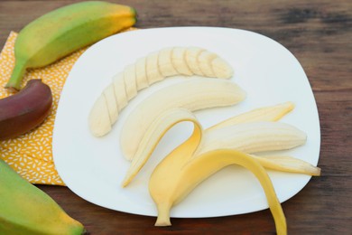 Photo of Whole and cut bananas on wooden table