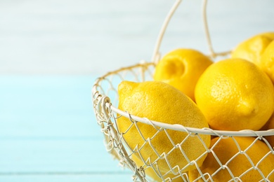 Photo of Basket with ripe lemons on table against light background, closeup
