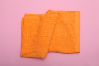 Photo of Folded orange beach towel on pink background, top view