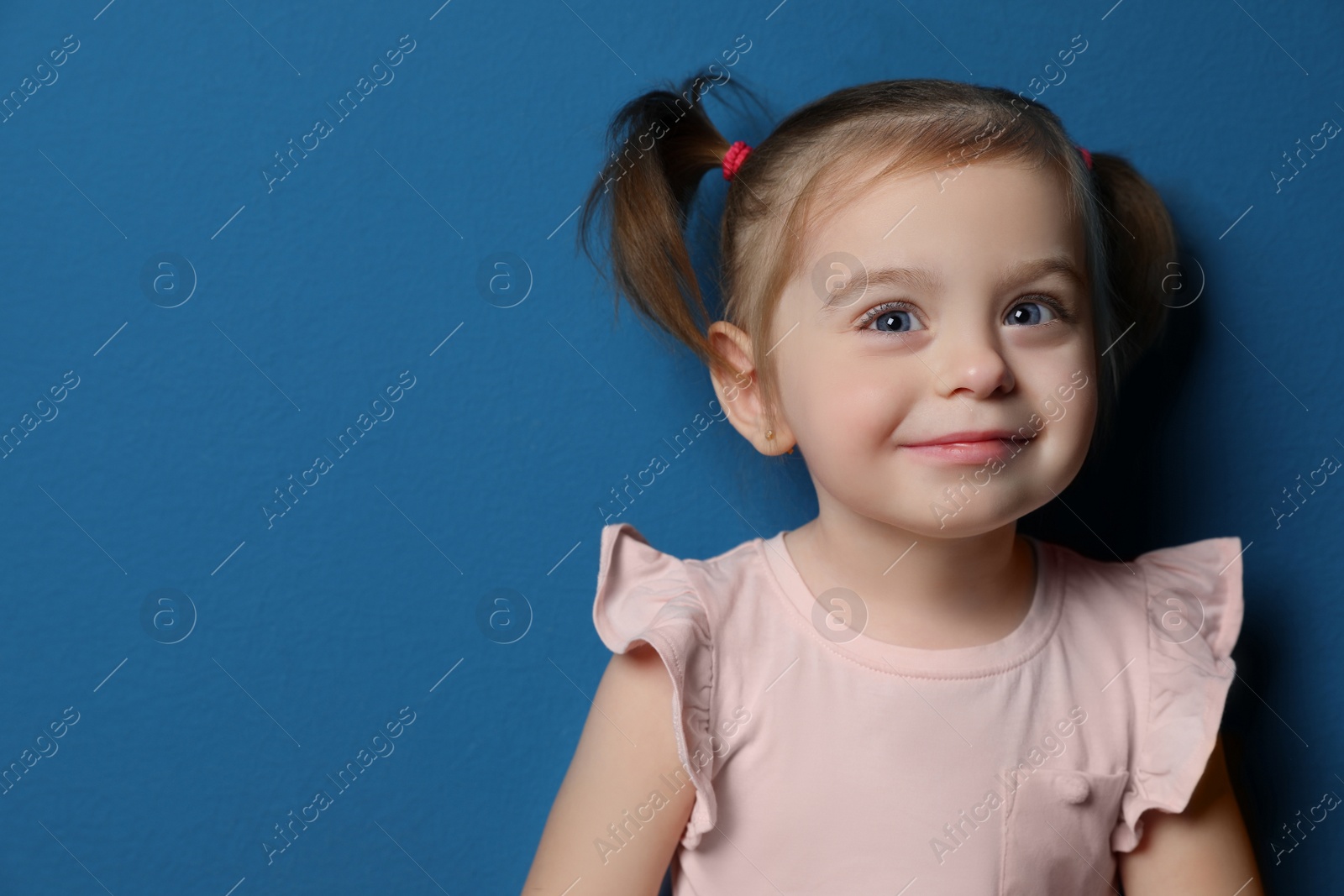 Photo of Portrait of cute little girl on blue background. Space for text