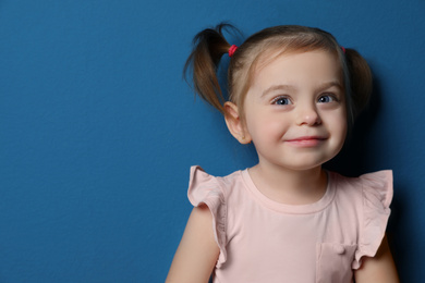 Photo of Portrait of cute little girl on blue background. Space for text