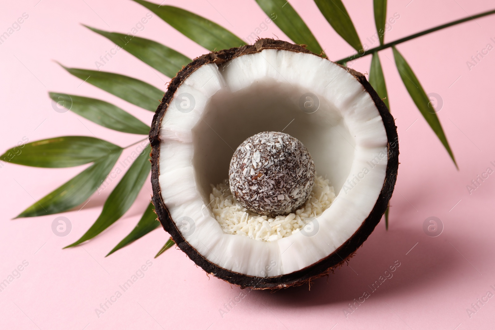 Photo of Composition with delicious vegan candy ball and coconut on pink background