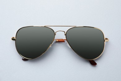 Photo of New stylish elegant sunglasses on white background, top view