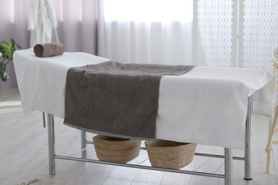 Photo of Comfortable massage table with clean towels in spa center