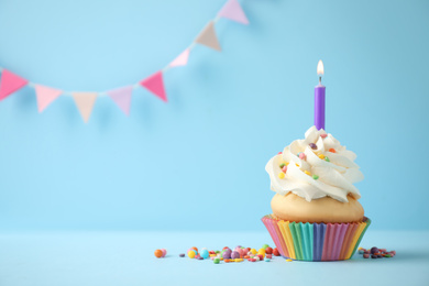 Delicious birthday cupcake with candle on light blue background. Space for text