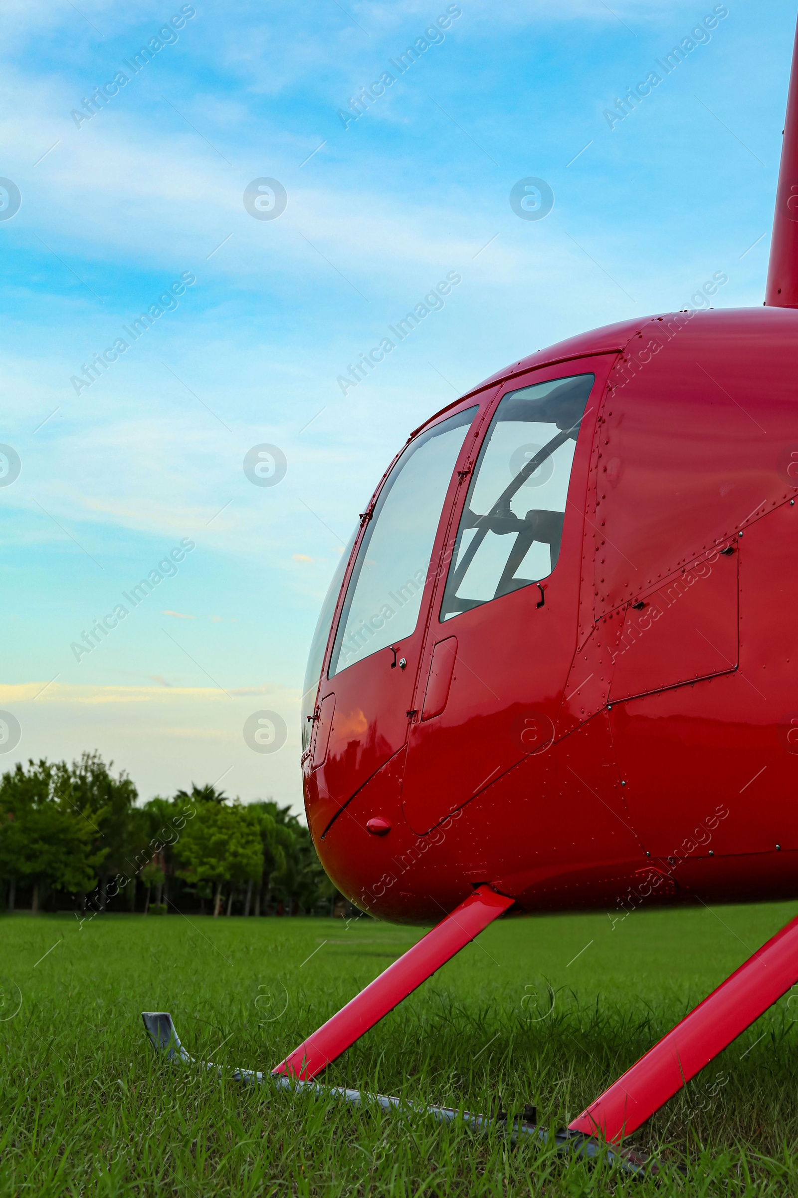 Photo of Modern red helicopter on green grass outdoors