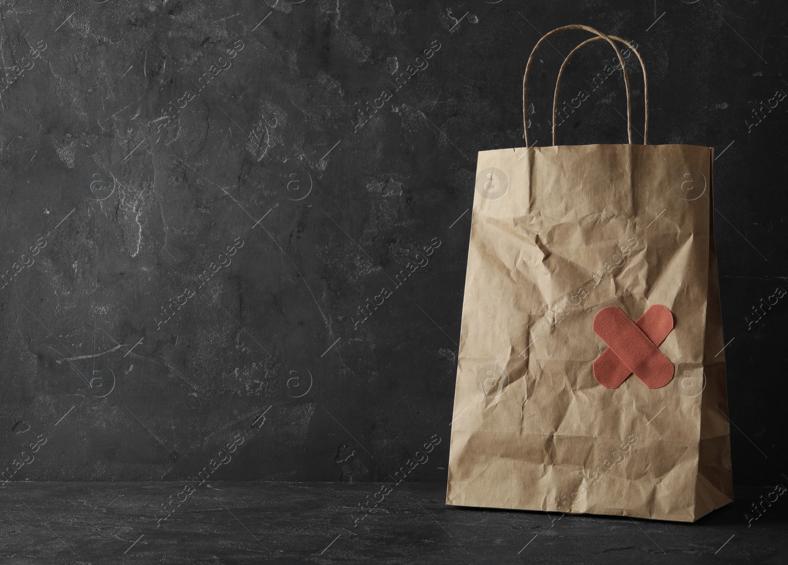 Photo of Shopping bag with sticking plasters on grey stone table, space for text