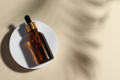 Photo of Bottle of cosmetic oil on beige background, top view. Space for text