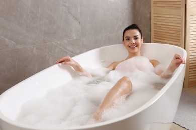 Photo of Woman taking bath with shower gel indoors