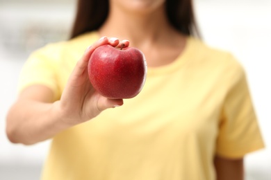 Photo of Woman holding fresh red apple indoors, closeup