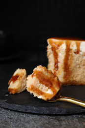 Slice of delicious cake with caramel sauce on slate board