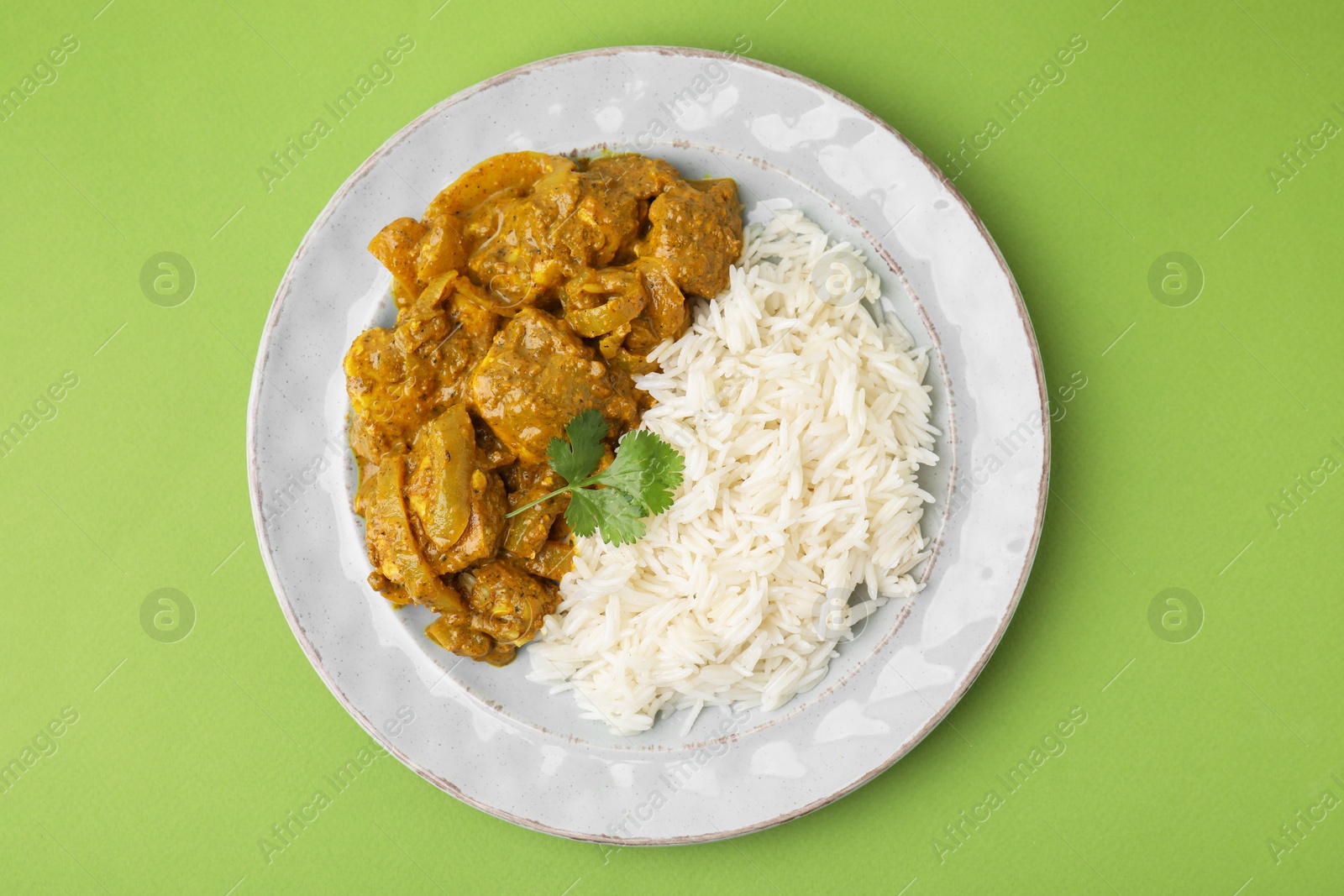 Photo of Delicious chicken curry with rice on green background, top view