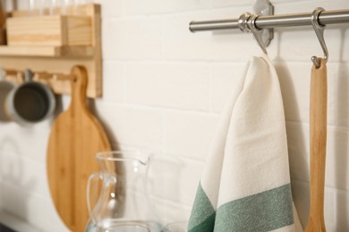 Photo of Clean towel and utensil hanging on rack in kitchen, closeup