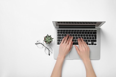 Photo of Woman using laptop at white table, top view. Space for text