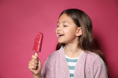 Photo of Adorable little girl with delicious ice cream against color background