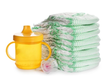Stack of disposable diapers and baby accessories on white background