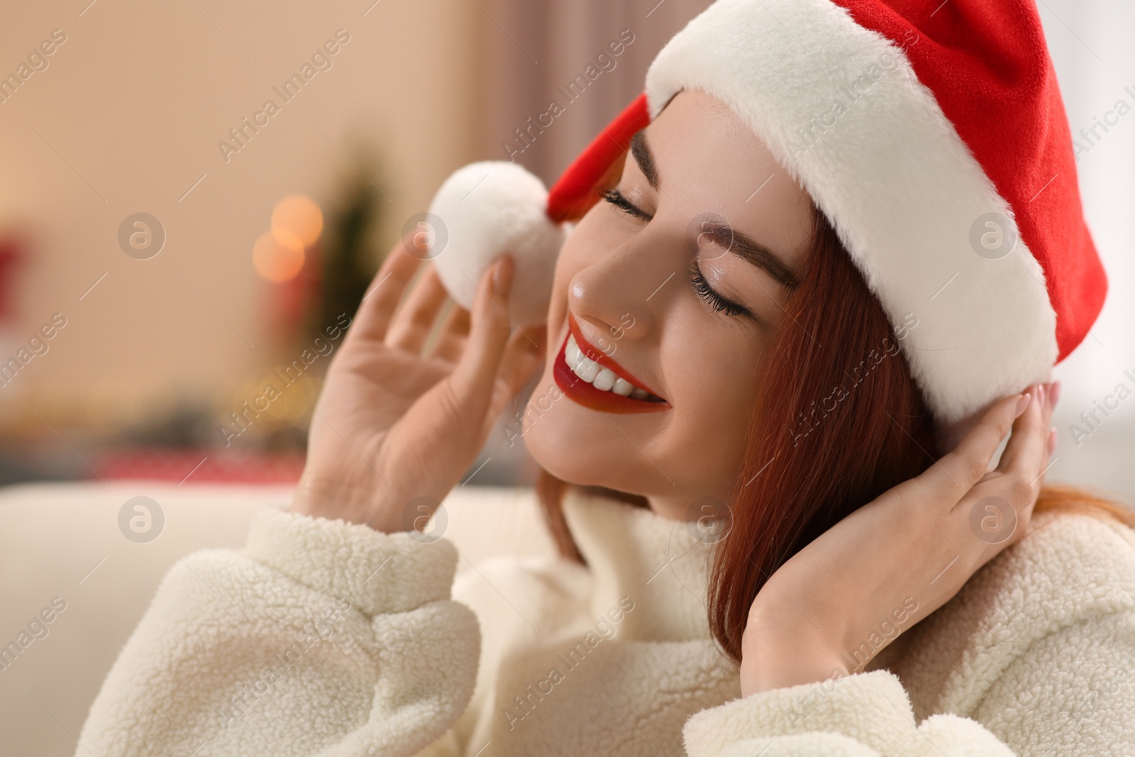 Photo of Beautiful young woman in Santa hat at home, space for text. Celebrating Christmas