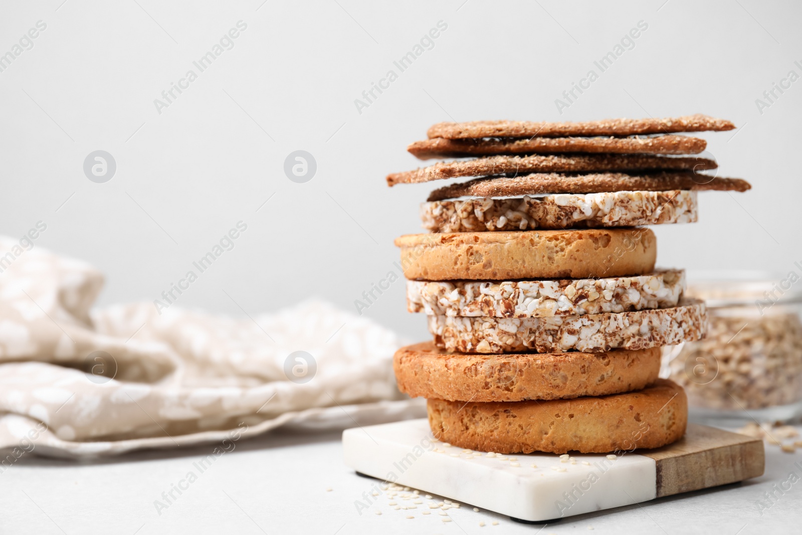 Photo of Stack of rye crispbreads, rice cakes and rusks on white table, space for text