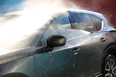 Cleaning automobile with high pressure water jet at car wash