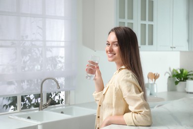 Woman with glass of tap water in kitchen