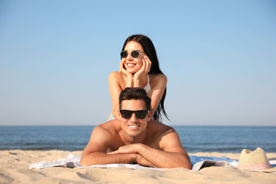 Happy couple resting on sunny beach at resort