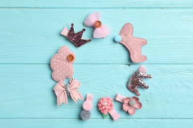 Frame of cute hair clips on light blue wooden table, flat lay. Space for text