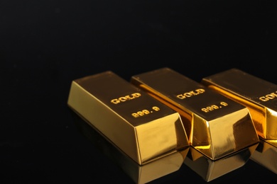 Shiny gold bars on black background, closeup. Space for text