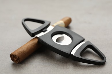 Photo of Cigar with guillotine cutter on light grey table, closeup