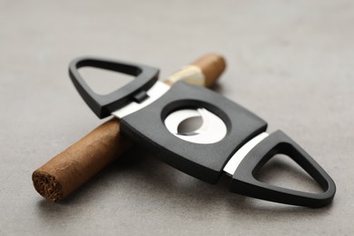 Cigar with guillotine cutter on light grey table, closeup