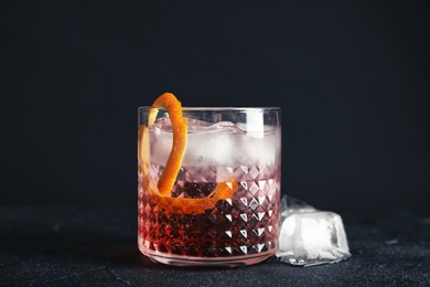 Photo of Glass of refreshing cocktail with ice cubes on dark background