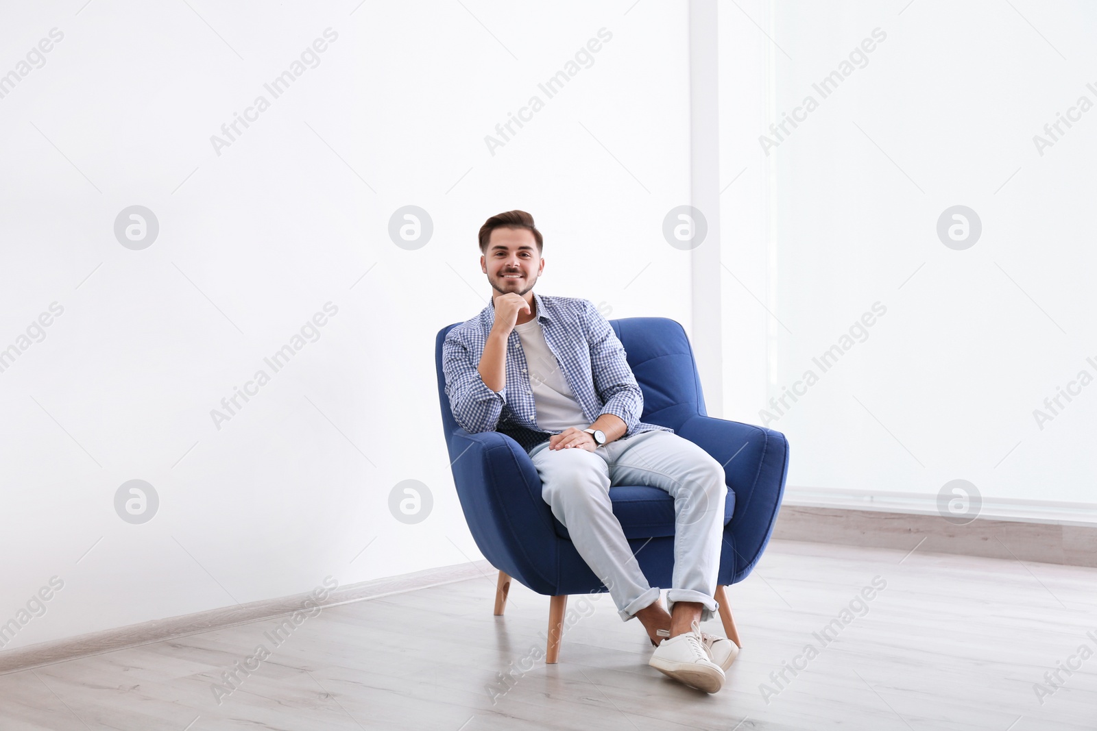 Photo of Handsome young man sitting in armchair indoors
