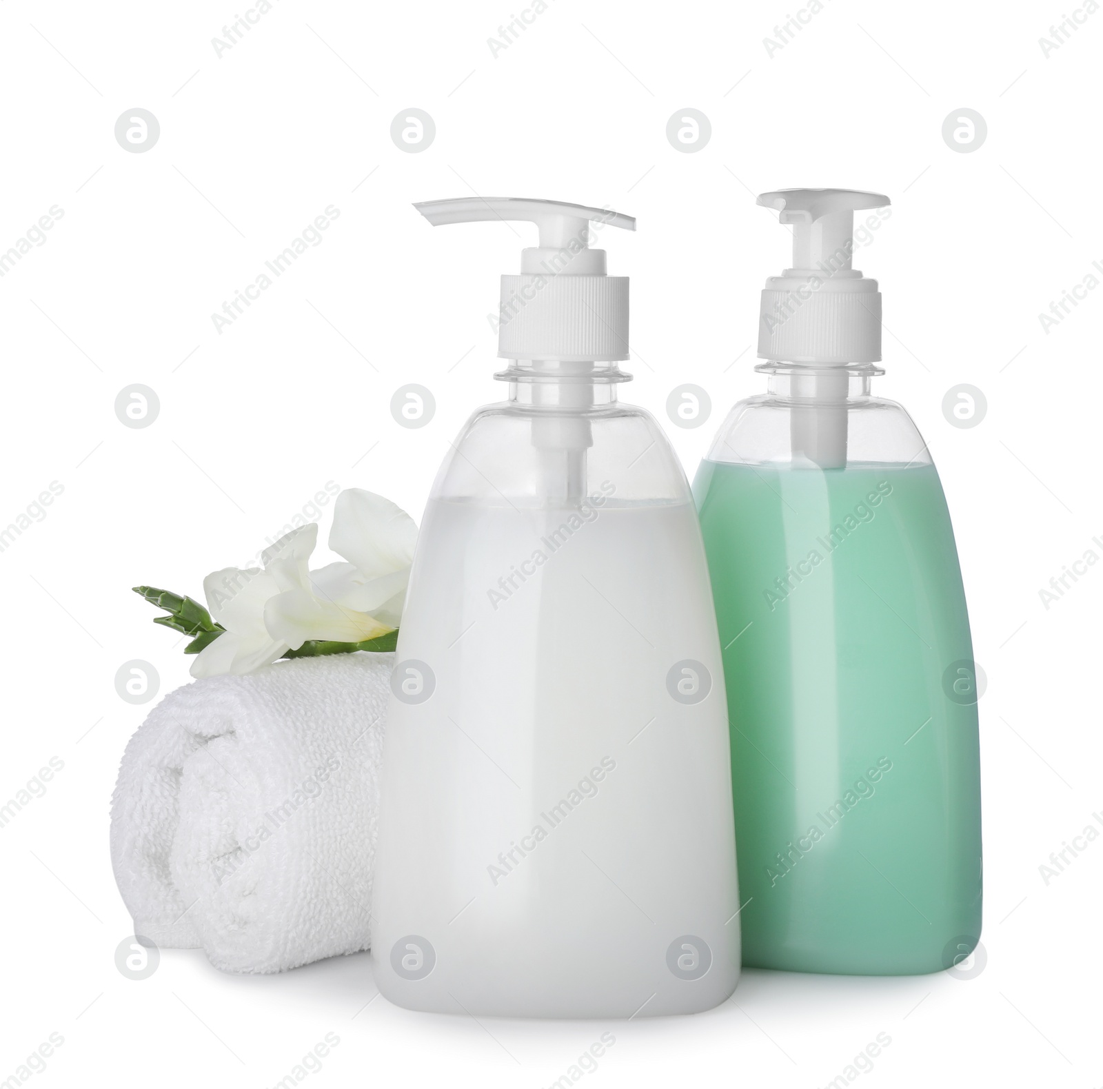 Photo of Dispensers of liquid soap, rolled towel and freesia flowers on white background