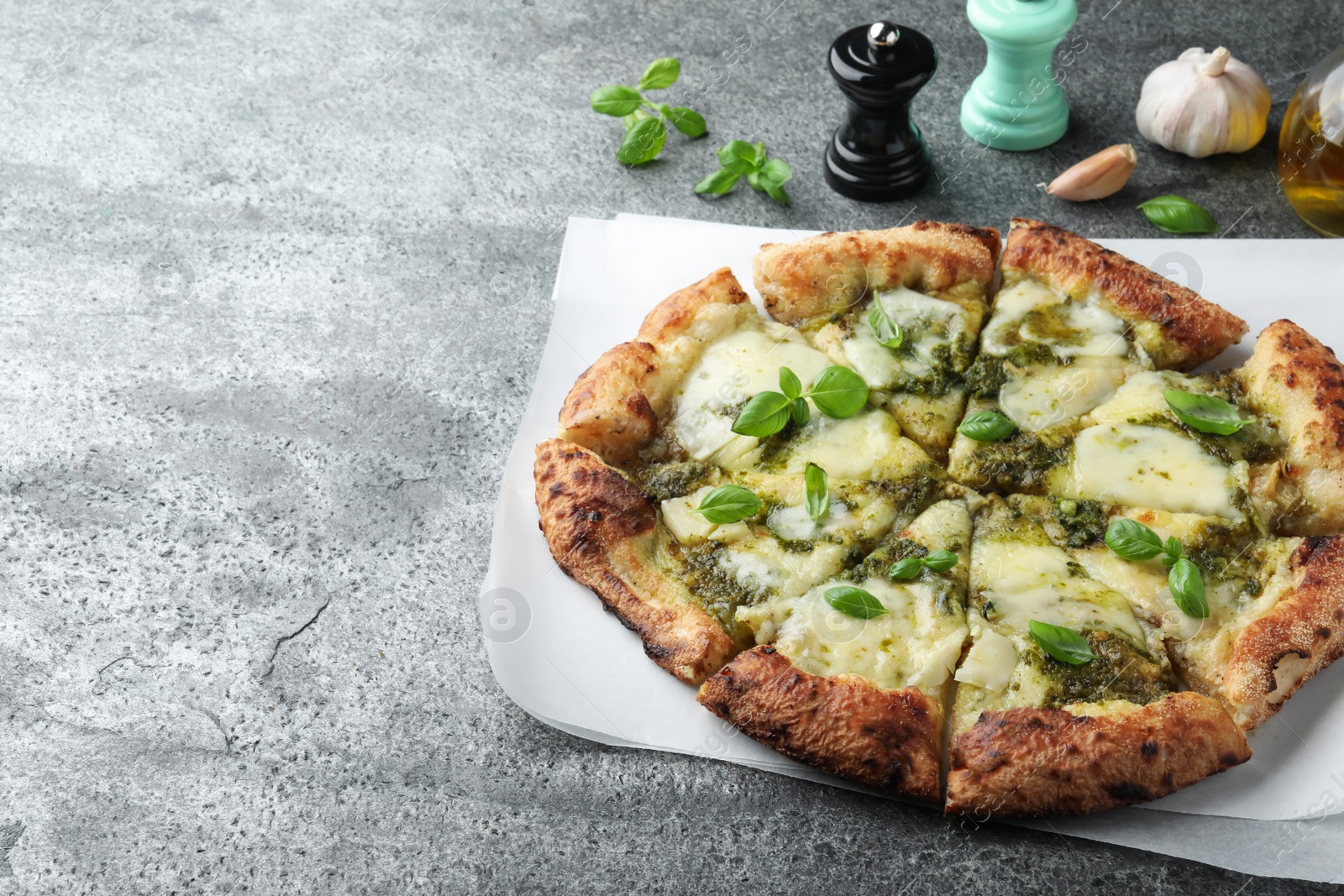 Photo of Delicious pizza with pesto, cheese and basil on grey table. Space for text